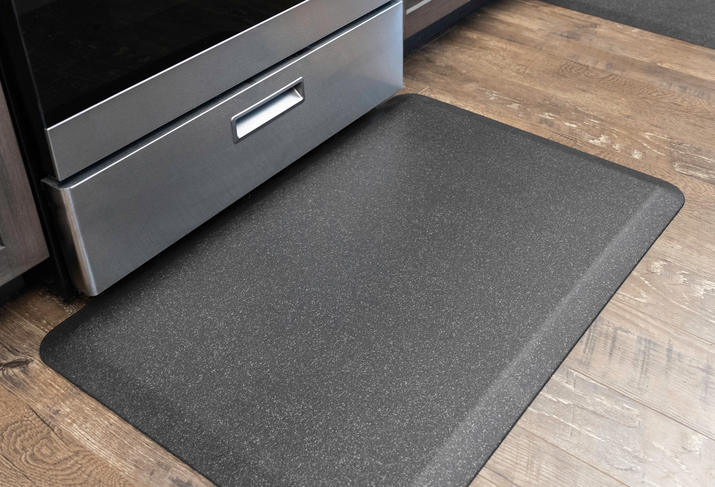 Granite steel WellnessMat on wood floor in front of kitchen stove