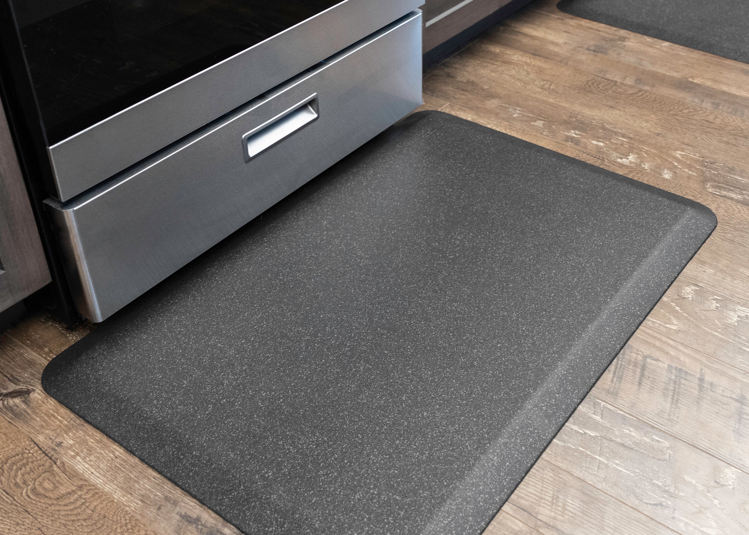 Granite steel WellnessMat on wood floor in front of kitchen stove