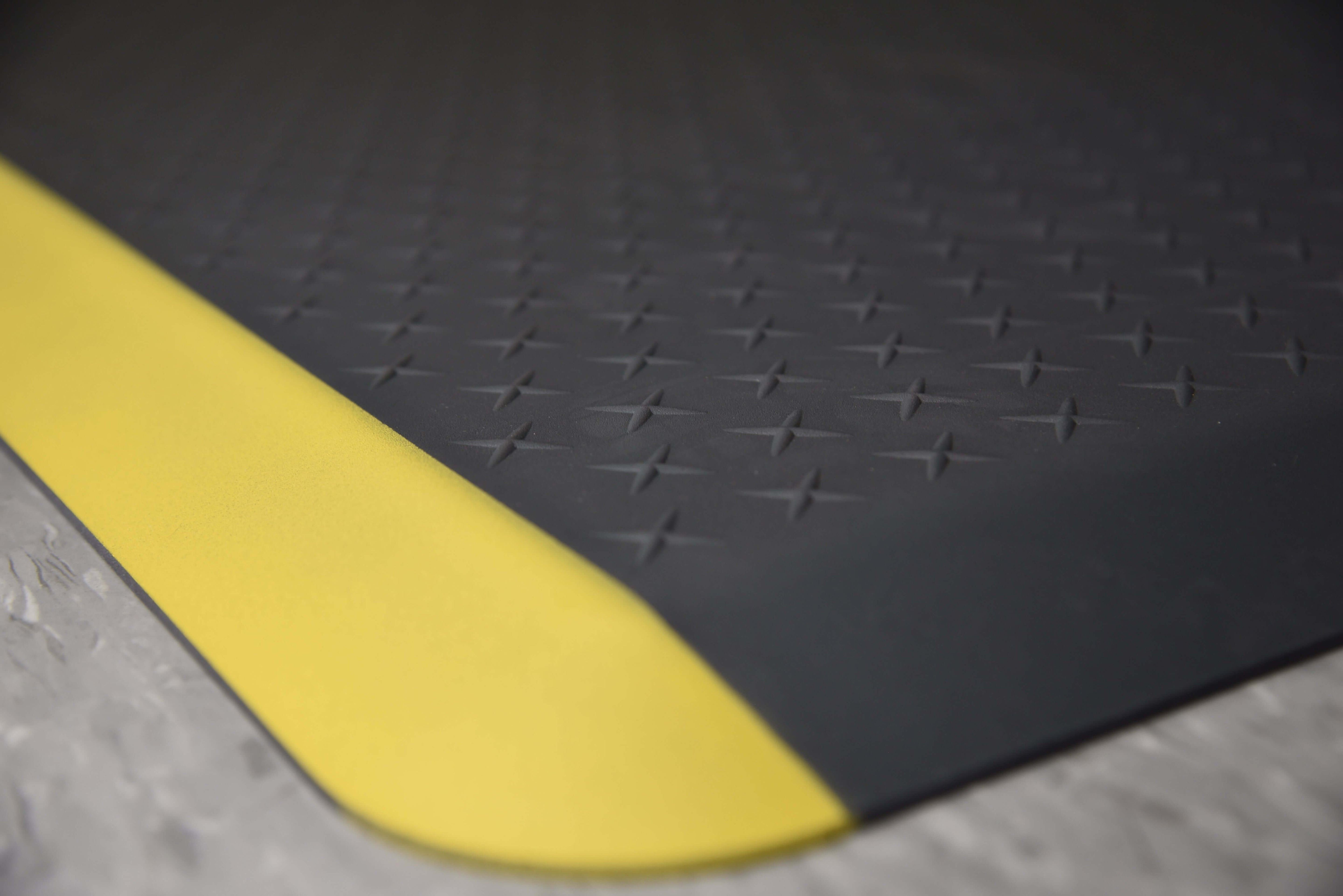 Corner shot of black Traxtion mat with yellow safety strip.