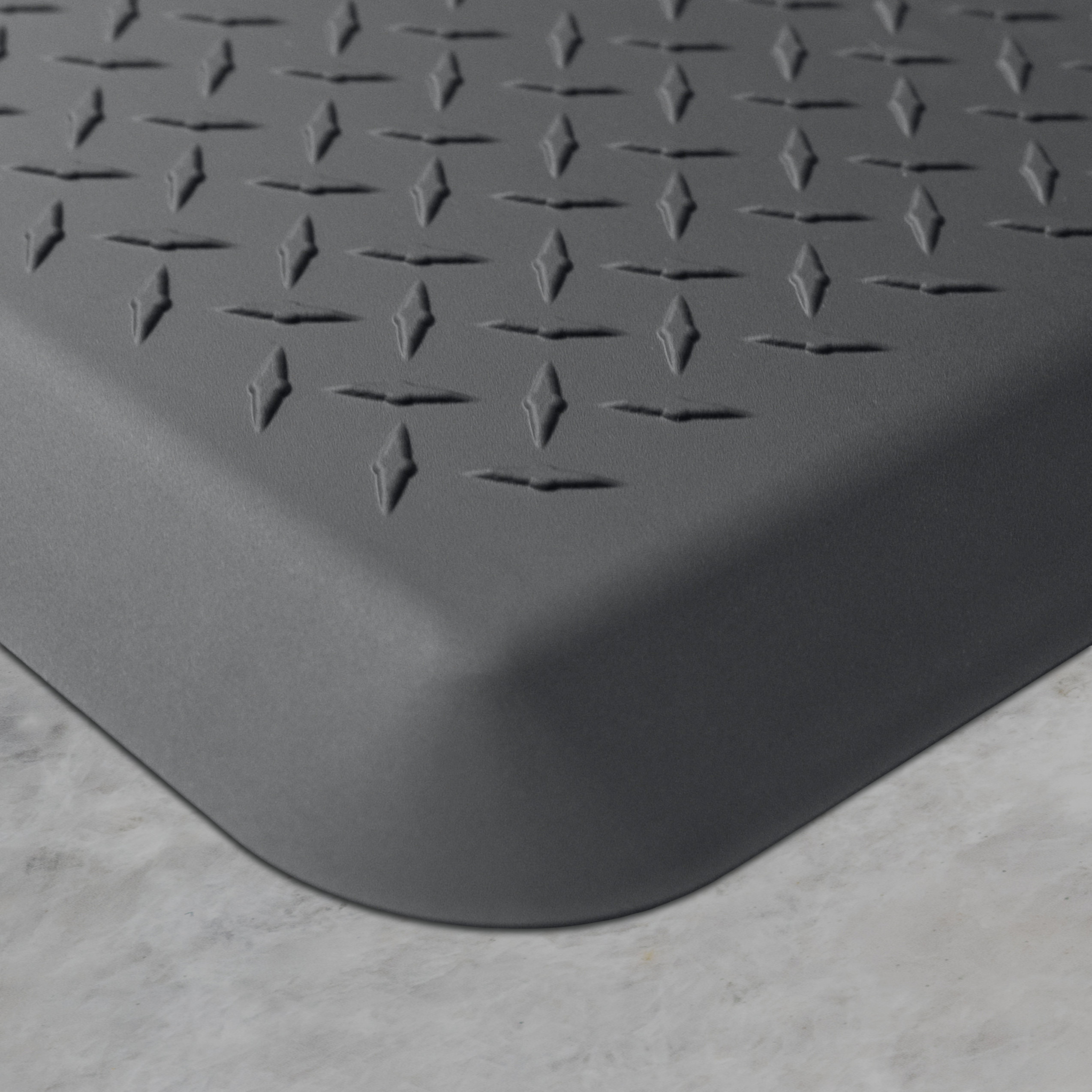 Up close corner of a gray Maxum mat on a concrete floor.