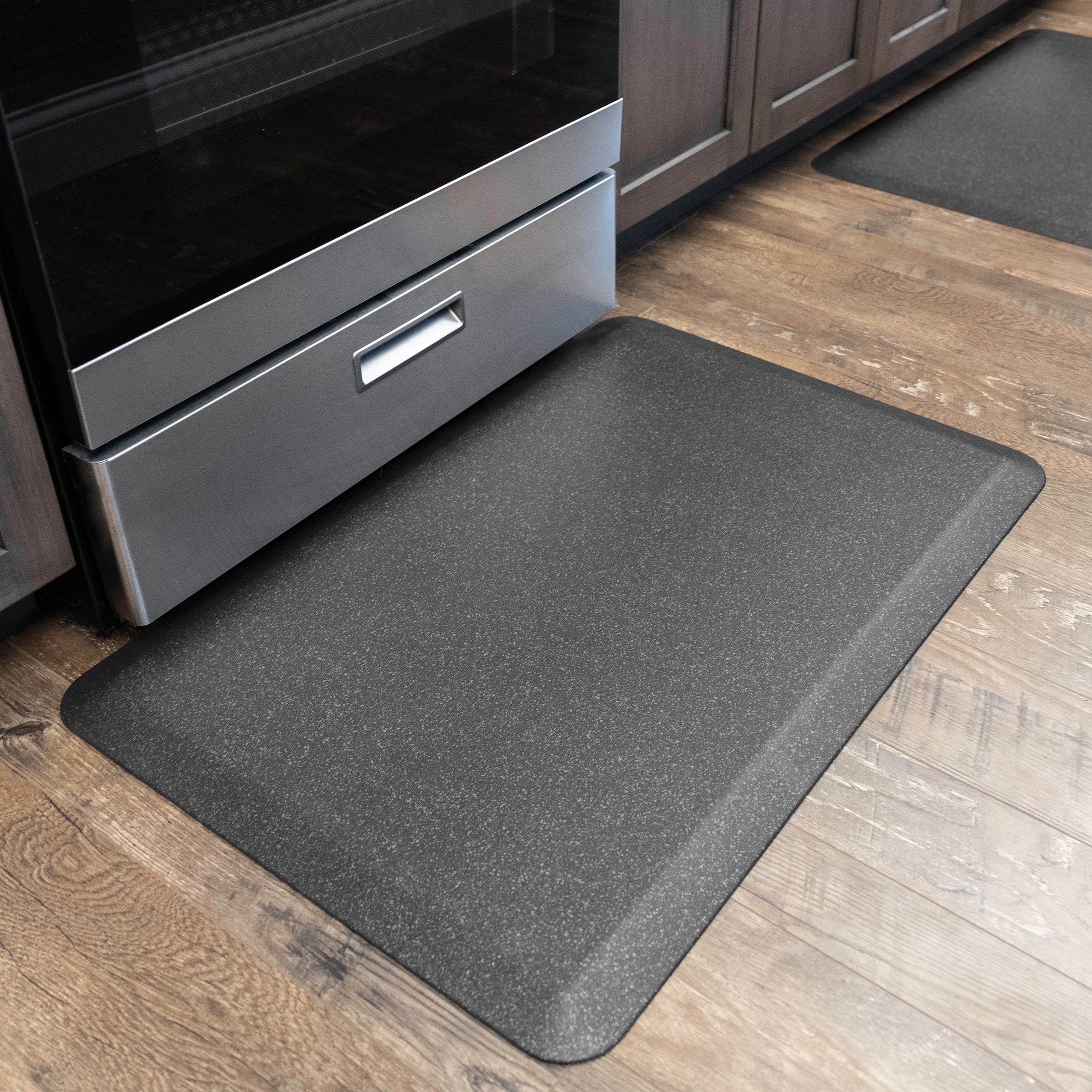 Granite steel WellnessMat on wood floor in front of kitchen stove 