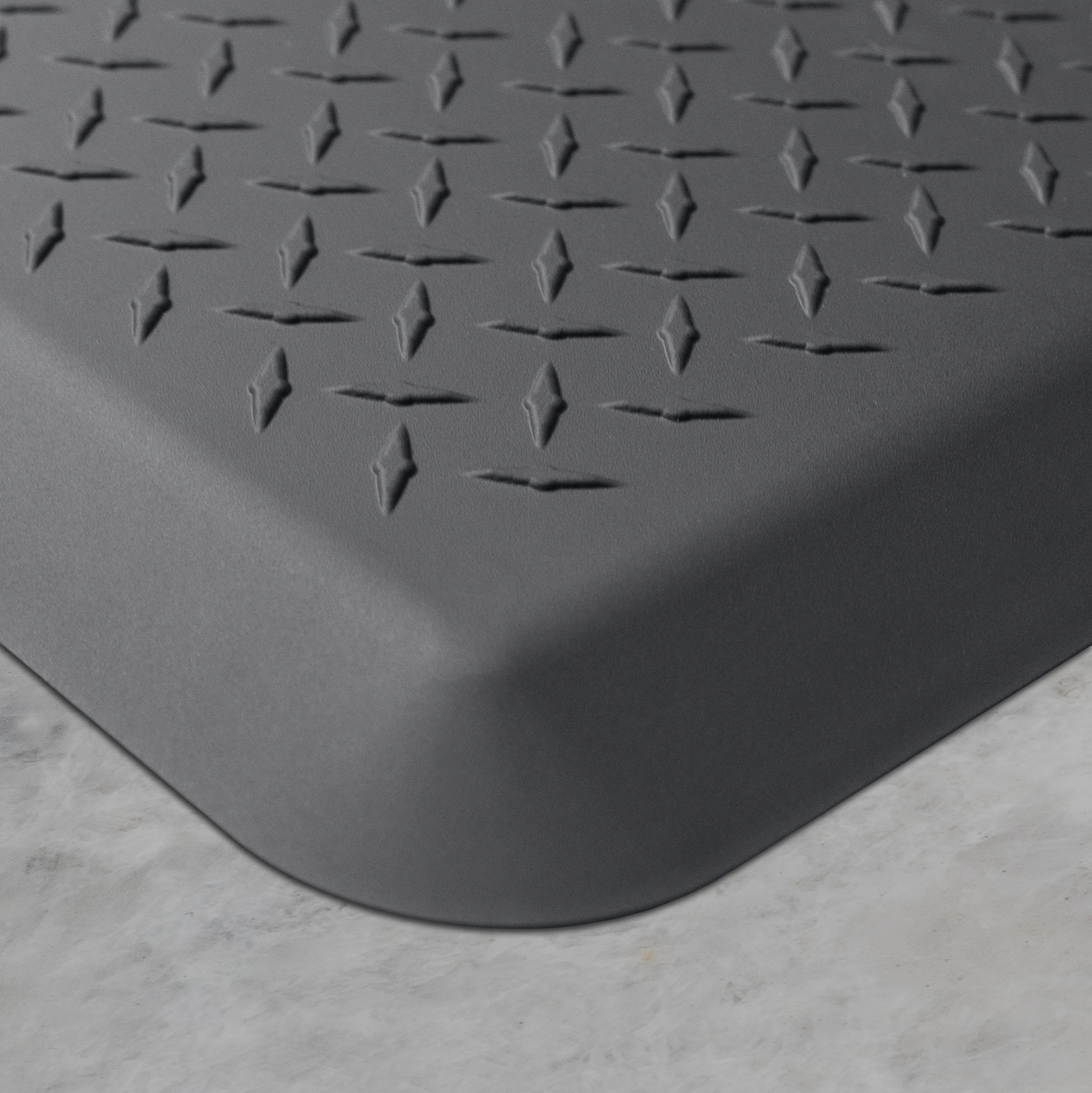 Up close corner of a gray Maxum mat on a concrete floor.